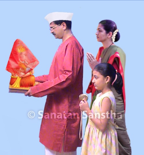 Photo of a male in Hindu attire carrying a covered Ganesh murti in his hands, accompanied by others